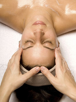 woman getting a head massage with cream in a spa